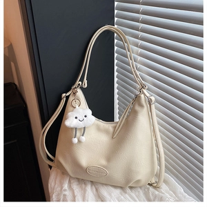 Detail view of cream shoulder bag with faux leather texture and a cloud pendant