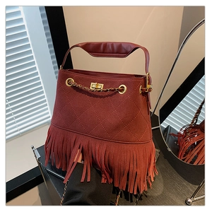 Détails d'un sac seau bordeaux matelassé avec chaîne dorée et longues franges élégantes