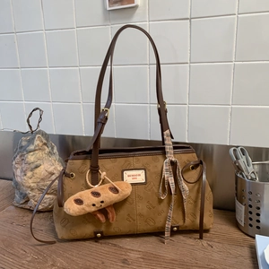 Détail du sac cabas marron caramel avec gaufrage de chat et breloque en peluche