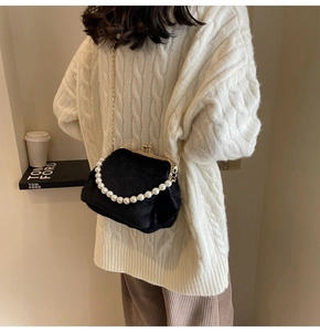 Détail d'un sac de soirée en peluche noire avec anse en perles et chaîne dorée