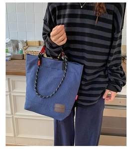Dettaglio della borsa tote a quadri blu con manico in corda e logo in pelle