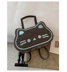 Detail view of cat-shaped brown faux leather bag with green embroidery and plaid sides
