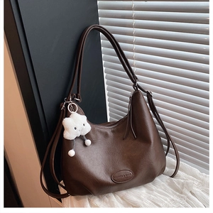 Detail of dark brown faux leather hobo bag with pebble texture and plush cloud charm