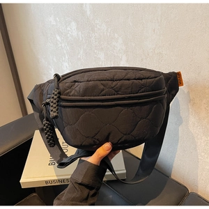 Detailaufnahme der gesteppten Nylon-Umhängetasche mit Doppelreißverschluss und Label