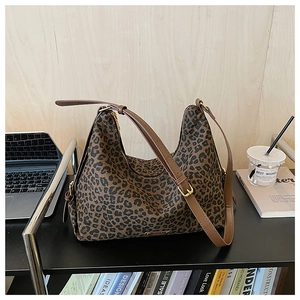 Detail der Leoparden-Einkaufstasche mit braunem Lederriemen neben Laptop und Kaffee