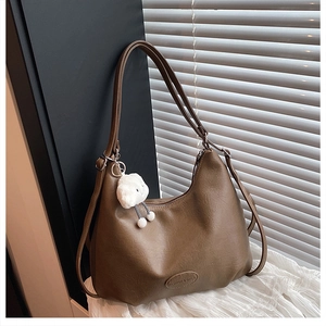 Detail of vintage brown PU leather shoulder bag with plush cloud charm and embossed logo