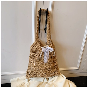 Detail of woven straw tote bag with white lace bow and pearl charms hanging on a door
