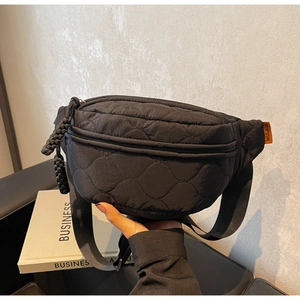 Détail du sac de poitrine noir matelassé avec surpiqûres losanges et étiquette orange