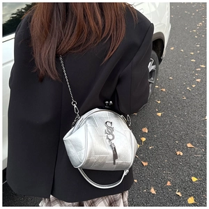 Detail der silbernen Metallic-Umhängetasche mit Leder-Patchwork und Quastenkette