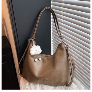 Close-up of coffee brown PU leather hobo bag with a cute white cloud plush pendant