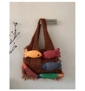 Detail of a brown woven tote bag featuring colorful fish toys and long tassels
