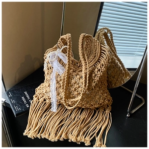 Detail view of khaki woven beach tote featuring handmade fringe and pearl lace accents
