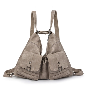 Front detail of khaki canvas backpack featuring symmetrical utility flap pockets and D-rings