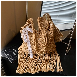 Close-up of handmade crochet beach tote with fringe detail and floral lace pearl charm