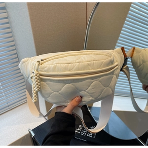 Détail du sac banane en toile matelassée avec tirette tressée et étiquette orange