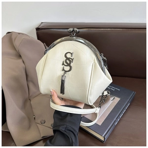 Detail der cremefarbenen Muscheltasche mit Patchwork-Lederstruktur und Metall-Quasten