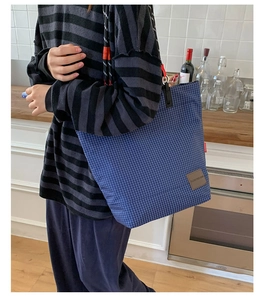Dettaglio della borsa tote a quadri blu con spalline in corda e logo MOBORN in pelle