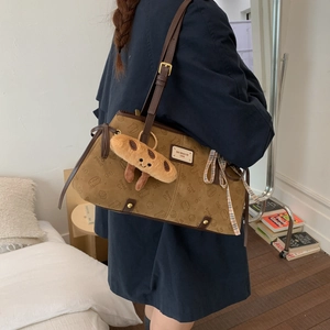 Détail d'un sac cabas en daim marron avec imprimés de chats et un charmant pain en peluche