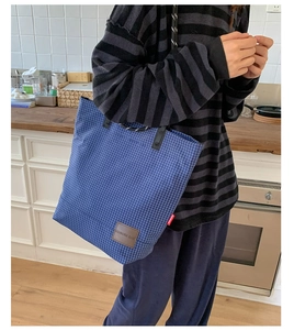 Dettaglio della borsa shopper a quadri blu con patch in pelle e etichetta rossa