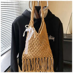 Detail of hand-woven beige tote bag featuring long tassels and a pearl bow charm