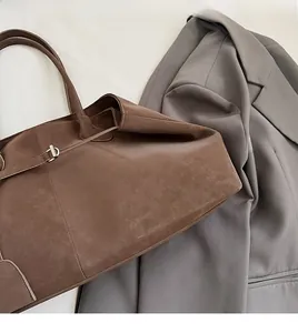 Detailed view of dark brown suede tote bag with decorative leather drawstring and buckle