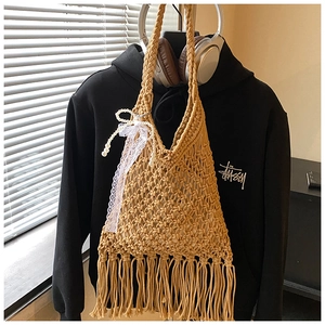 Detailed close-up of beige woven hollow mesh tote bag with long fringe and lace bow detail