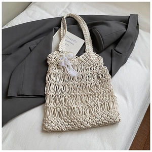 Detail of hand-woven mesh tote bag with lace bow and faux pearl pendant accessories