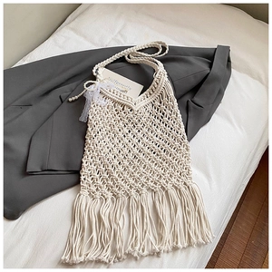 Detail of white woven beach tote with long tassels, pearl charm, and lace bow accent