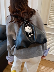 Large black leather tote bag with cloud charm shown on shoulder for daily fashion use