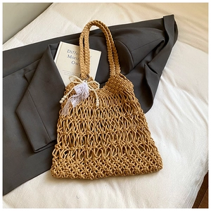 Detail of hand-woven hollow mesh tote bag featuring white lace bow and pearl charm