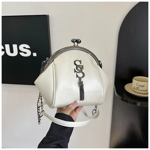 Detailansicht der cremefarbenen Muschel-Tasche aus Lychee-Leder mit Metallverschluss und Troddel