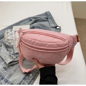 Gros plan sur le sac banane matelassé rose avec coutures ondulées sur fond en jean bleu