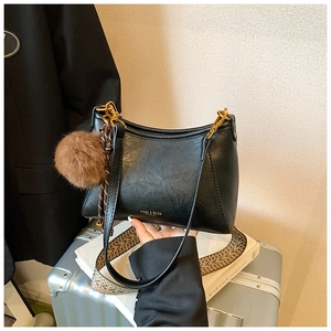 Close-up of black PU leather dumpling bag with decorative tassel and ethnic strap