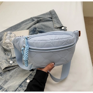 Gros plan du sac banane matelassé bleu clair avec texture en losanges et tirette tissée
