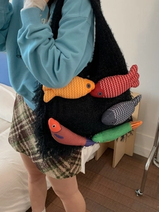 Large black plush tote bag with five colorful stuffed fish charms worn by a model