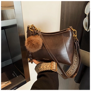 Detail of dark brown faux leather bag with ethnic strap and plush heart charm