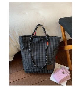 Dettaglio della toppa in pelle marrone e del manico in corda intrecciata della borsa