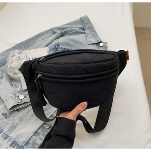Détail du sac ceinture matelassé noir avec coutures ondulées et étiquette orange