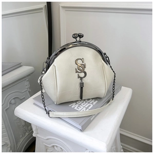 Detail der cremefarbenen Retro-Muscheltasche mit Metallverschluss, S-Logo und Quastenanhänger