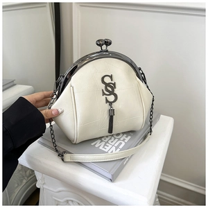 Detail der cremefarbenen Muscheltasche mit Metallfransen und Logo am Bügelverschluss