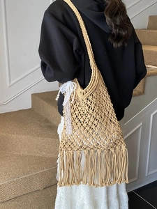 Handwoven hollow knit tote bag with fringe and lace bow, ideal for summer beach vacation