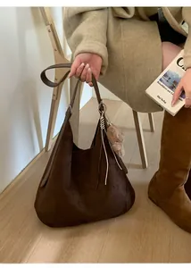 Detail of deep brown suede Hobo bag with wide strap and cute plush bear charm
