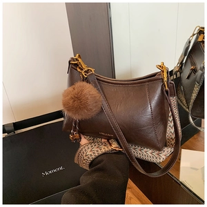 Detail of dark brown faux leather bag with wide ethnic strap and plush charm