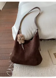 Detail of deep brown faux suede tote bag featuring a cute plush bear pendant accessory
