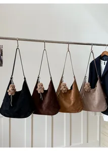 Hobo bags in black, brown and khaki suede material hanging with teddy bear pendants