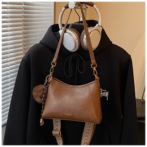 Brown PU leather croissant bag with fuzzy charm and patterned wide woven strap
