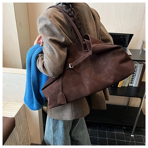 Detailed back view of a large brown suede tote bag worn by a model in a library