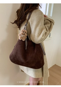 Detail of retro brown suede tote bag with plush bear charm and silver metal hardware