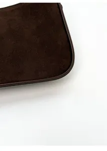 Close-up of deep brown suede texture and leather trim on the corner of the small square bag