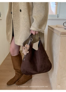 Detail of dark brown suede Hobo bag with plush dog charm and long leather shoulder strap